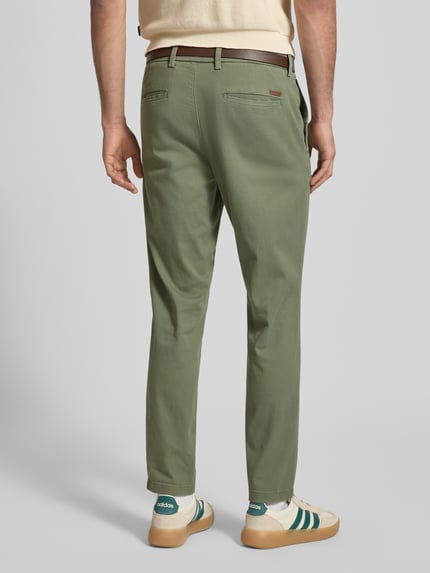 Männermodel trägt Slim Fit Stoffhose mit abnehmbarem Gürtel Modell 'Marco' von JACK & JONES aus elastischem Baumwoll-Mix, grün, Gesäßtaschen, Eingrifftaschen, Ganzkörperansicht Rückansicht.
