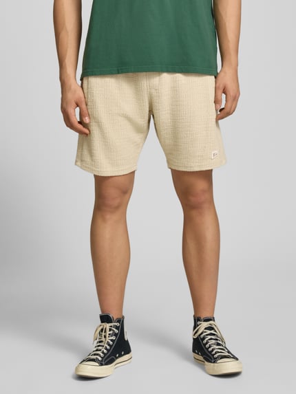 Männermodel trägt Shorts mit Label-Patch Modell 'LIBCO' von Pegador aus Material-Mix mit Strukturmuster, Gerader-Schnitt, Nahaufnahme Oberkörper.
