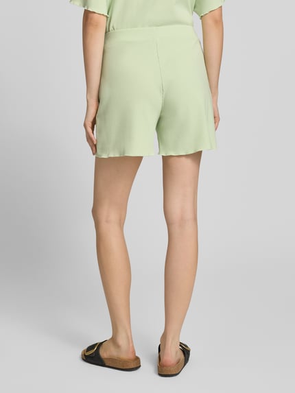 Frauenmodel trägt Shorts in Ripp-Optik Modell 'Lyle' von OH APRIL in Hellgrün mit elastischem Bund, Regular Fit, Ganzkörperansicht Rückansicht.