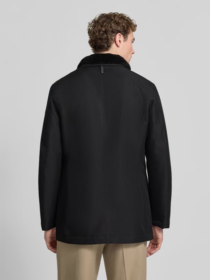 Männermodel trägt Kurzmantel mit Stehkragen Modell 'DARRY' von JOOP!, schwarze Webware, strukturierte Optik, Longline, Ganzkörperansicht Rückansicht.