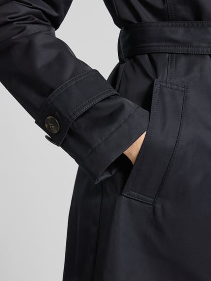Frauenmodel trägt Regular Fit Mantel mit Umlegekragen von Fuchs Schmitt aus glattem, dunkelblauem Baumwoll-Mix, Detailaufnahme Tasche.
