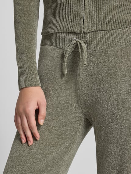 Frauenmodel trägt Sweathose mit Tunnelzug von Juicy Couture in unifarbener Optik mit Kordeln und Gummizug, Nahaufnahme Oberkörper.