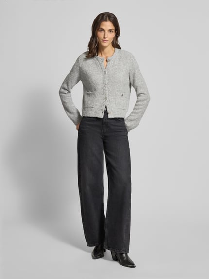 Frauenmodel trägt Strickjacke mit Knopfleiste von Rich & Royal in Grau, lockerer Schnitt, gerippte Abschlüsse, Ganzkörperansicht von vorne.
