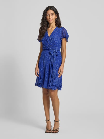 Frauenmodel trägt Knielanges Kleid mit V-Ausschnitt Modell 'WANDELLA' von Lauren Ralph Lauren in Blau mit Wickel-Optik, Taillengürtel, Paisley-Muster, blickdichtes Unterkleid, taillierter Schnitt, Ganzkörperansicht von vorne.