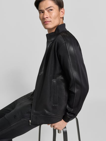 Mannenmodel draagt Jacke aus Baumwoll-Mix in Leder-Optik van Diesel in zwart met Steekzakken en ritssluiting, Recht pasvorm, Nahaufnahme bovenlichaam. Context: Heren jack van Diesel, katoenmix, recht pasvorm, leerlook, steekzakken, ritssluiting, ruglengte maat M: 65 cm, schouderbreedte maat M: 46 cm, mouwlengte maat M: 65 cm.