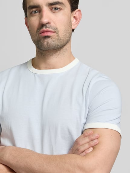 Männermodel trägt Slim Fit T-Shirt mit Rundhalsausschnitt von MCNEAL in Weiß, reine Baumwolle, kurzärmelig, Nahaufnahme Oberkörper.