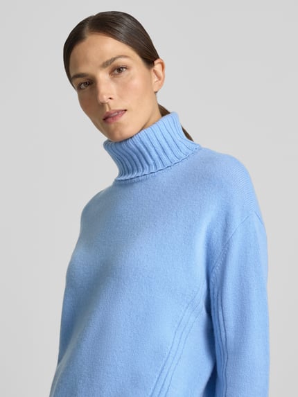 Frauenmodel trägt Relaxed Fit Rollkragenpullover aus reiner Wolle von Liu Jo White in Hellblau, gerippte Abschlüsse, Nahaufnahme Oberkörper.