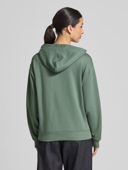 Frauenmodel trägt Hoodie mit Tunnelzug Modell 'IMA' von MSCH Copenhagen in Grün, gerade Form, Rückenansicht, Ganzkörperansicht Rückansicht.