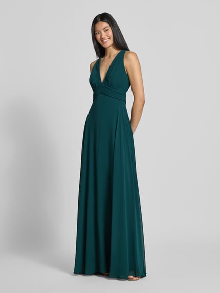 Frauenmodel trägt Fit and Flare Abendkleid mit tiefem V-Ausschnitt von Jake*s Cocktail in dunklem Grün, fließender Stoff, Ganzkörperansicht von vorne.