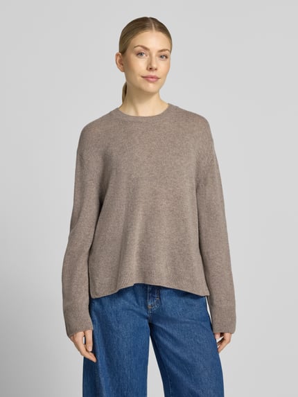 Frauenmodel trägt Loose Fit Pullover aus reiner Wolle von Marc O'Polo in Beige, kombiniert mit blauer Jeans, Ganzkörperansicht von vorne, Damen Pullover von Marc O'Polo.