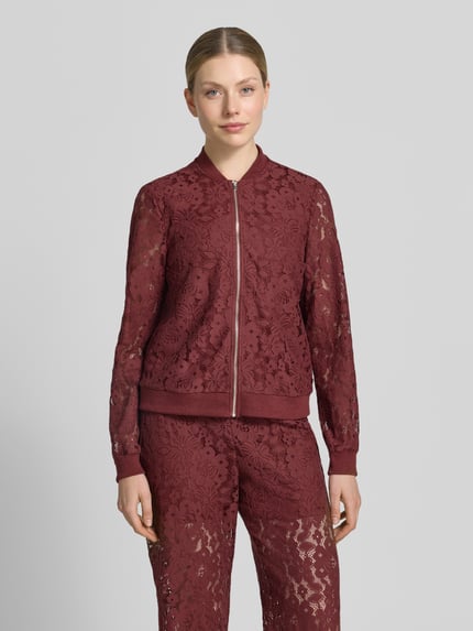 Frauenmodel trägt Regular Fit Blouson aus Baumwoll-Mix Modell 'HONEY' von Vero Moda in Florales-Allover-Muster, Häkel-Material, Reißverschluss, Kragenform: College-Look, gerippte Bündchen, Farbton Bordeaux, Optik:Allover-Muster, Nahaufnahme Oberkörper.