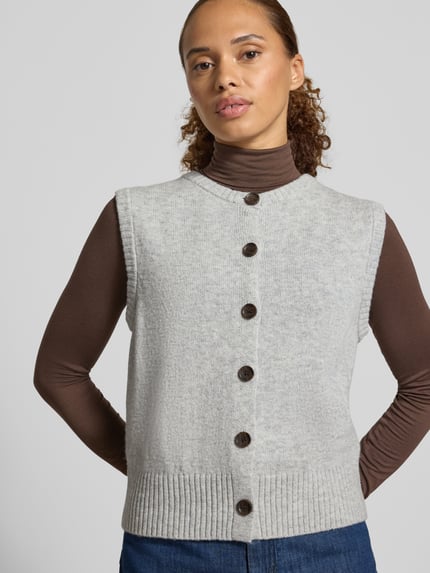 Frauenmodel trägt Regular Fit Strickweste aus Woll-Mix von Christian Berg in Hellgrau mit Knopfleiste, Ärmelos, gerippte Abschlüsse, Ganzkörperansicht von vorne, Damen Strickweste, Rückenlänge S: 45 cm.