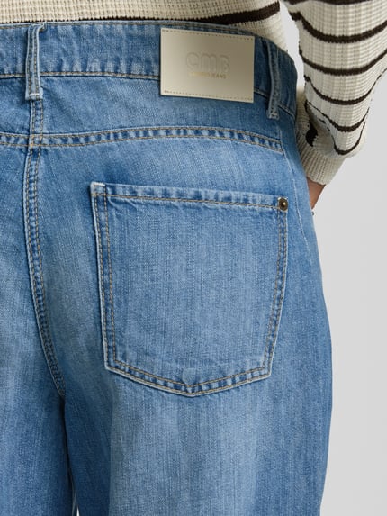 Frauenmodel trägt Barrel Jeans aus Baumwoll-Leinen-Mix Modell 'ORIA' von Cambio in Denim-Optik mit Nieten, Label-Patch und 5-Pocket-Design, Detailaufnahme Rückansicht.