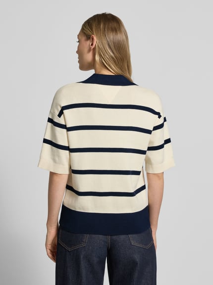 Frauenmodel trägt Regular Fit Pullover aus reiner Baumwolle von Tommy Hilfiger mit dunkelblauem Streifenmuster, Feinstrick, Polokragen, Logo-Stitching, gerippten Abschlüssen, Ganzkörperansicht Rückansicht.