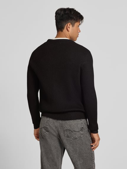 Männermodel trägt Strickpullover mit Rundhalsausschnitt Modell 'PANNEL' von JACK & JONES, Material-Mix, schwarze Farbe, Ganzkörperansicht Rückansicht.