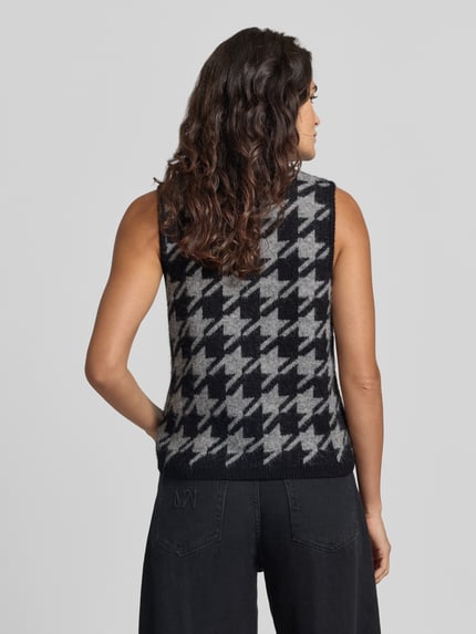 Frauenmodel trägt Pullunder mit Schluppe Modell 'VMMARLENA' von VERO MODA im Hahnentritt-Jacquard, Strickoptik, Ganzkörperansicht Rückansicht.