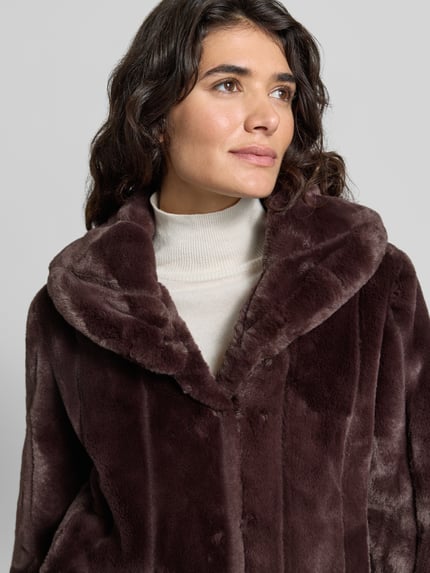Kobiece model prezentuje kurtkę z sztucznego futra Model 'NEW SOPHY' od GUESS, krój regular fit, wykładany kołnierz, zbliżenie na górną część ciała. Długość tyłu w rozmiarze S: 58 cm, szerokość ramion w rozmiarze S: 42 cm, szerokość w rozmiarze S: 52 cm, długość rękawów w rozmiarze S: 62 cm.