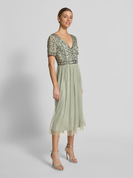 Modelka kobieca nosi Knielanges Kleid mit floralem Pailettenbesatz od LACE & BEADS, jasnozielony mesh, kwiatowe cekiny, krój slim fit, dekolt V, krótki rękaw, długość tyłu w rozmiarze S: 100 cm, szerokość w rozmiarze S: 42 cm, długość rękawa w rozmiarze S: 19 cm, pełny widok z przodu