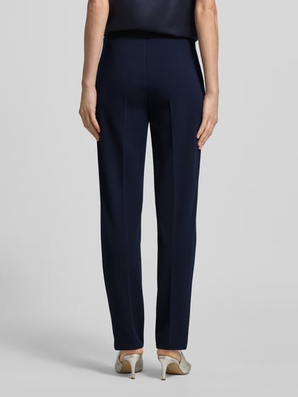 Vrouwenmodel draagt Slim Fit stoffen broek met strookzakken van Vera Mont, donkerblauw, elastische materiaalmix, smalle pijpen, siernaden, elastische band, strookzakken met ritssluiting, binnenbeenlengte maat 36 is 72 cm, bandwijdte maat 36 is 28 cm. Volledige lichaamsopname achteraan.