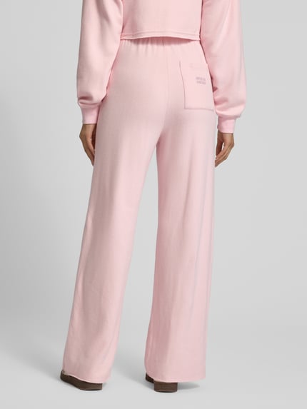 Frauenmodel trägt Wide Leg Sweathose mit elastischem Bund von American Vintage in Rosa, Baumwoll-Mix mit Stretch-Anteil, Ganzkörperansicht Rückansicht