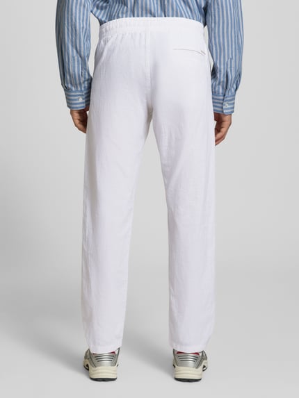 Männermodel trägt białe spodnie z bawełniano-lnianej mieszanki Jack & Jones, krój regular fit, model 'KANE', elastyczny pas, szerokość w rozmiarze M: 41 cm, długość wewnętrzna nogawki w rozmiarze M: 81 cm, widok całej sylwetki z tyłu.