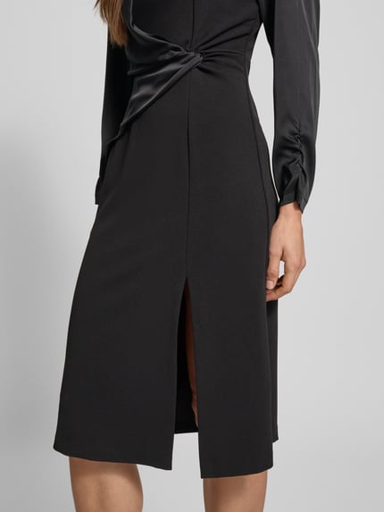 Frauenmodel trägt Cocktailkleid mit Raffungen von Rinascimento, schwarzer Material-Mix mit Stretch-Anteil, Gehschlitz, Nahaufnahme Unterkörper.
