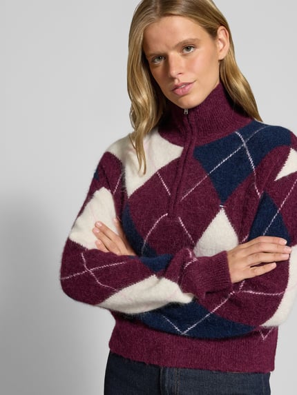 Frauenmodel trägt Regular Fit Pullover aus Alpaka-Woll-Mix von Tommy Jeans in Burgunder, Dunkelblau und Weiß, Grobstrick, Nahaufnahme Oberkörper. Damen Pullover von Tommy Jeans.