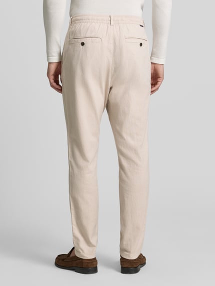 Mężczyznamodel nosi Regular Fit Chino aus Baumwoll-Mix od Tom Tailor, kolor melanż, boczne kieszenie, bawełna mieszanka, widok całej sylwetki z tyłu.