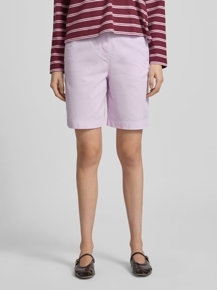 Vrouwenmodel draagt Regular Fit Chino-Shorts uit katoen-lyocell-mix van Tommy Hilfiger, effen kleuren, regular fit, logostitching, knoop- en ritssluiting, zijsteekzakken, achterzakken, mix van katoen en lyocell, voorkant geheel lichaam.