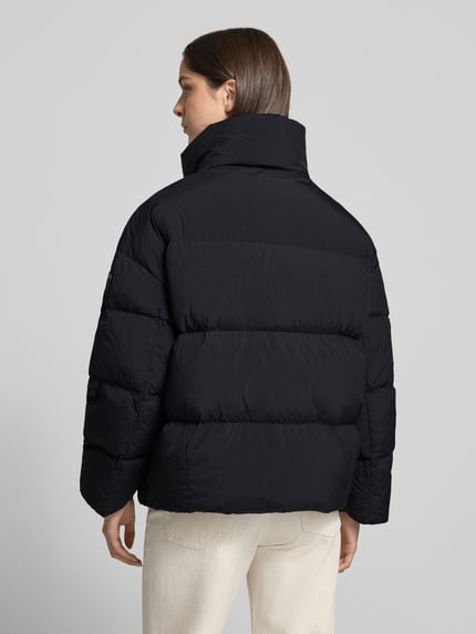 Frauenmodel trägt Wendejacke mit Steppnähten Modell 'ROSS' von Blauer USA in Schwarz, glatte Struktur, Rückenansicht, Ganzkörperansicht Rückansicht. Damen Wendejacke, Relaxed Fit, Umlegekragen, Eingrifftaschen, Rückenlänge 65 cm, Schulterbreite 54 cm, Brustweite 61 cm, Ärmellänge 51 cm.