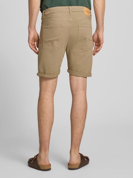 Männermodel trägt Jeansshorts mit Umschlag und Eingrifftaschen Modell 'RICK ALLEN' von Jack & Jones, beige, Baumwoll-Elasthan-Mix, Ganzkörperansicht Rückansicht.