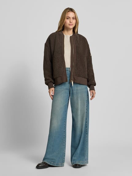 Frauenmodel trägt braune Teddyjacke mit Stehkragen Modell 'Emeline' von MOS MOSH, lockere Passform, Ganzkörperansicht von vorne.