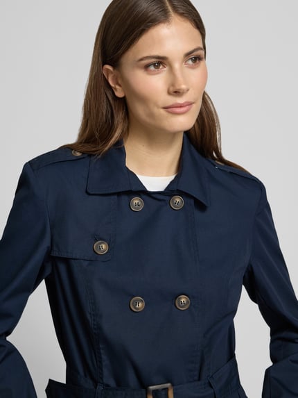 Frauenmodel trägt Regular Fit Mantel mit Umlegekragen Modell 'Lora' von Soyaconcept, dunkelblauer Material-Mix mit Baumwoll-Anteil, 2-reihige-Knopfleiste, taillierte Passform, abnehmbarer Stoffgürtel, Eingrifftaschen, Nahaufnahme Oberkörper.