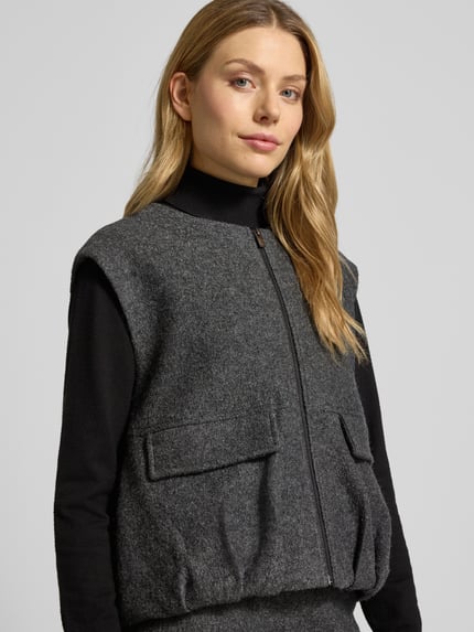 Vrouwenmodel draagt Weste mit Reißverschluss Modell 'Womaya' van OPUS in grijze viscose-wolmix met ronde hals en klepzakken, regular fit, detailopname bovenlichaam.