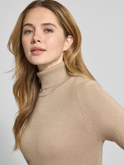 Frauenmodel trägt Slim Fit Rollkragenpullover aus Viskose-Mix Modell 'HAPPYSHINE' von Vero Moda, schimmernd, unifarben, Nahaufnahme Oberkörper.