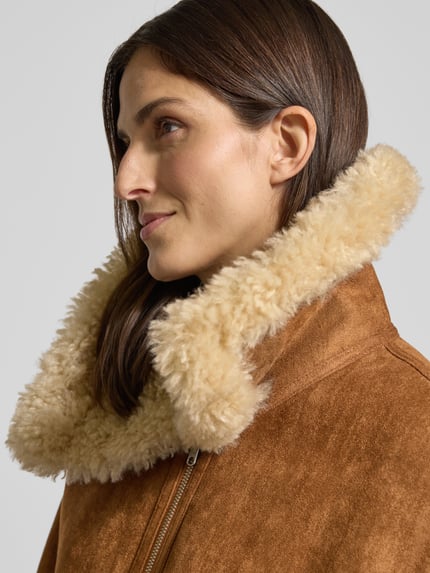 Frauenmodel trägt Jacke mit Futter aus Teddyfell Modell 'ADRIANA' von Mango in Braun mit Umlegekragen, Nahaufnahme Oberkörper.