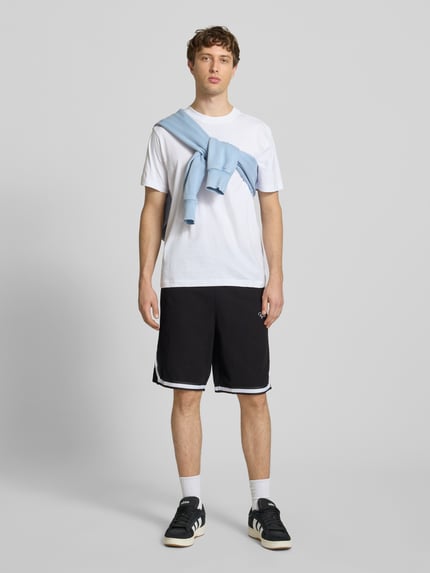 Männermodel trägt Shorts mit Logo-Stitching Modell 'Signar' von Pegador in Schwarz mit Kontraststreifen, Reine Baumwolle, Gerader-Schnitt, Ganzkörperansicht von vorne.