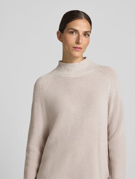 Frauenmodel trägt Relaxed Fit Strickpullover mit Kaschmir-Anteil von Luisa Cerano in hellem Beige, gerippter Kragen, Nahaufnahme Oberkörper. Baumwoll-Mix, langärmelig, gerippte Ärmelabschlüsse.