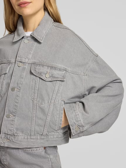 Vrouwenmodel draagt oversized grijze jeansjack van model 'PAASITHE' van Armedangels, mix van katoen en lyocell, denimlook, lange mouw, steekzakken, borstzakken, platte kraag, knoopsluiting met labelpatch. Nahaufnahme bovenlichaam