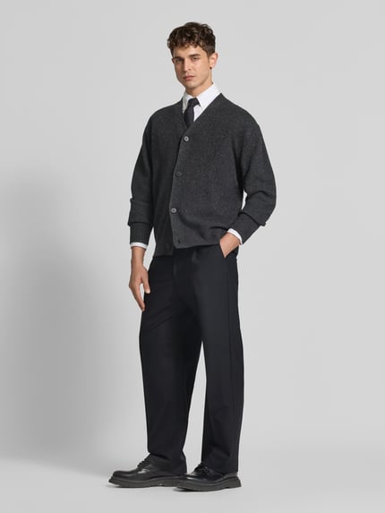 Männermodel trägt Straight Fit Stoffhose mit Bundfalten von ANNARR in Schwarz, kombiniert mit Hemd und Strickjacke, Ganzkörperansicht von vorne. Herren Stoffhose, Knopf- und Reißverschluss, Eingrifftaschen, Leistentaschen am Gesäß, Innenbeinlänge 81 cm, Bundweite 48 cm.