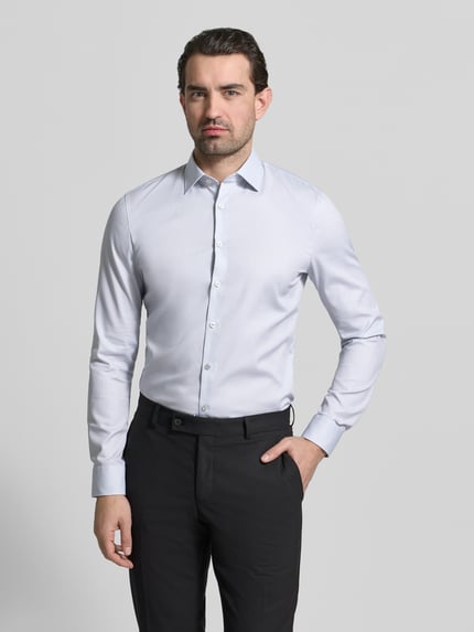Männermodel trägt Slim Fit Businesshemd mit Kentkragen von OLYMP No. Six in Hellblau, glatte Textur, Durchgehende Knopfleiste, Ganzkörperansicht von vorne.