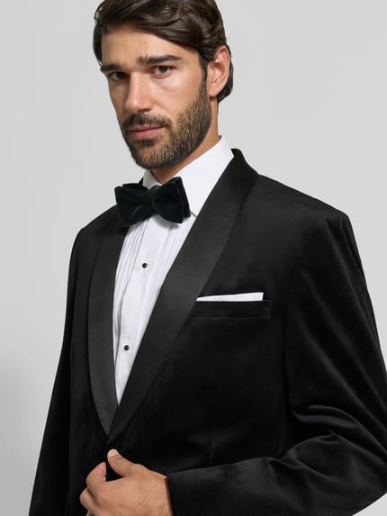 Męski model nosi Slim Fit Anzug aus Samt von Lindbergh, czarny aksamit, szalowy kołnierz, poszetka, zapięcie na guzik, Nahaufnahme górnej części ciała.