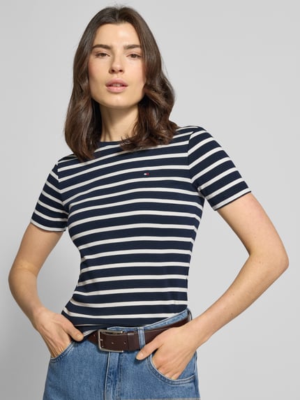 Frauenmodel trägt Slim Fit T-Shirt aus reiner Baumwolle von Tommy Hilfiger, Optik: Unifarben, Logo-Stitching, Rundhals, Kurzarm, Jersey, Ganzkörperansicht von vorne.