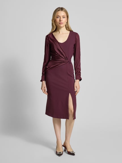 Frauenmodel trägt Cocktailkleid mit Raffungen von Rinascimento in dunklem Burgunderrot, taillierter Schnitt, Gehschlitz, Ganzkörperansicht von vorne.