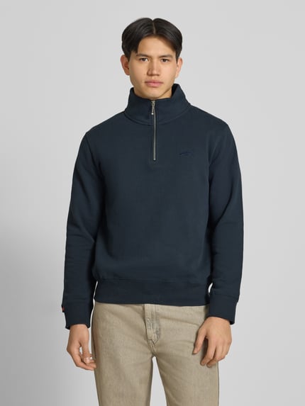 Männermodel trägt Sweatshirt mit Reißverschluss und Label-Stitching von Superdry, Baumwoll-Mix, Regular-Fit, Stehkragen, Ganzkörperansicht von vorne.