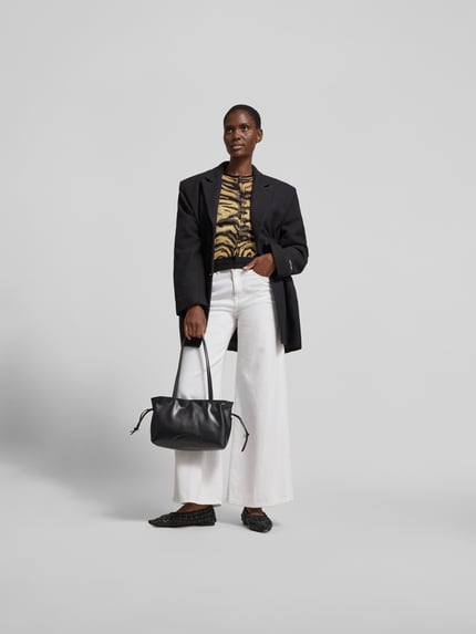 Männermodel trägt Shoulder Bag mit Raffungen Modell 'Ella' von Tory Burch, schwarz, strukturierte Oberfläche, ganzkörperansicht von vorne, główna komora z zapięciem na magnes, wąskie ramiączka na ramię, wewnętrzna kieszeń na zamek, szerokość w rozmiarze 1: 24 cm, długość w rozmiarze 1: 20 cm, głębokość w rozmiarze 1: 10 cm