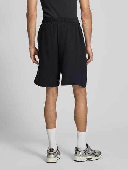 Männermodel draagt Regular Fit Shorts met elastische band van KARL KANI, puur katoen, structuurpatroon, kleur zwart, ganzekörperaanzicht rückansicht.