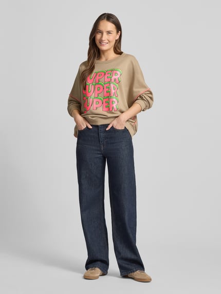 Vrouwenmodel draagt Oversized Sweatshirt met geribde boorden van miss goodlife in beige met statement-print, gemaakt van katoen, voorkant volledig lichaam.