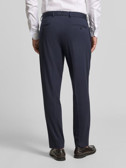 Männermodel trägt Regular Fit Anzughose mit Bügelfalten Modell 'Rennet' von JOOP!, dunkelblau, Material-Mix, Ganzkörperansicht Rückansicht.
