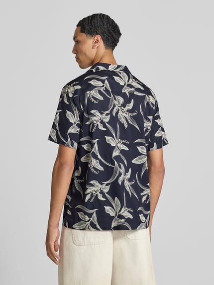 Männermodel trägt Regular Fit Freizeithemd mit Reverskragen von Superdry, florales Muster in Schwarz und Beige auf Baumwolle, Ganzkörperansicht Rückansicht. Rückenlänge 66 cm, Schulterbreite 41 cm, Ärmellänge 18 cm, Modern Fit, Knopfleiste.